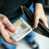 Ręce trzymają polskie banknoty 200 zł i pusty portfel. Zastanawiasz się, ile trwa zasiłek dla bezrobotnych?