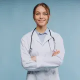 Uśmiechnięta lekarka w białym kitlu ze stetoskopem, zastanawia się, ile zarabia psychiatra.