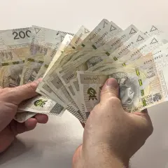 Ręce trzymające plik banknotów 200 zł. Dyskusja na forum: przeliczenie emerytury po 65 roku życia.