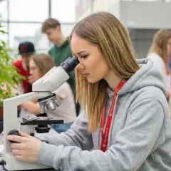 Młoda technik ochrony środowiska bada próbki pod mikroskopem w laboratorium.