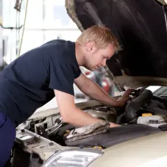 Mężczyzna pracuje przy silniku samochodu, ucząc się na kursie mechanika samochodowego dla dorosłych.