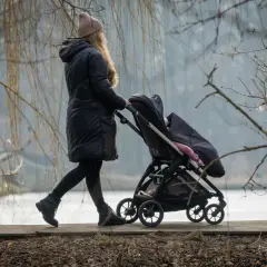 Kobieta na urlopie macierzyńskim spaceruje z dzieckiem w wózku. Zastanawia się, urlop macierzyński ile płatny, by zapewnić dziecku wszystko, co najlepsze.