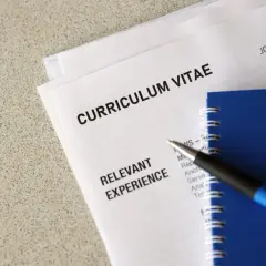 Długopis leży na dokumentach z nagłówkiem "CURRICULUM VITAE" i sekcją "RELEVANT EXPERIENCE". To klauzula CV po angielsku, gotowa do uzupełnienia.
