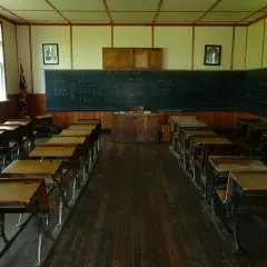Klasa szkolna z ławkami i tablicą, gdzie widnieje statut szkoły.