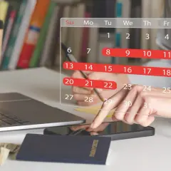 Planowanie urlopu: 26 dni wolnego do wykorzystania. Na biurku laptop, paszport, pieniądze i kalendarz.