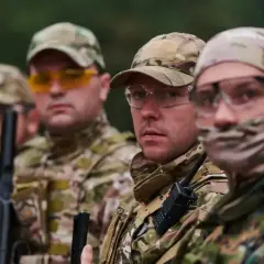 Grupa żołnierzy w kamuflażu, jeden z nich to starszy szeregowy specjalista, gotowi do akcji.