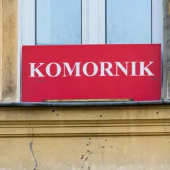 Czerwony szyld z napisem "KOMORNIK" nad oknem. Może oznaczać, że to miejsce, gdzie można dowiedzieć się o kwocie wolnej od zajęcia.