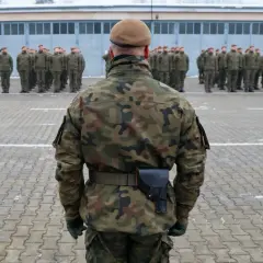 Żołnierz w mundurze polowym stoi na placu apelowym przed szeregiem innych żołnierzy. Czy w wieku 35 lat można iść do wojska? Tak, wiek nie jest przeszkodą.