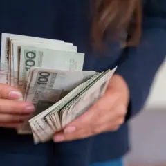 Dłonie liczą banknoty 100 zł. To portierka, która właśnie otrzymała zapłatę za swoją pracę.