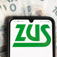 Telefon z aplikacją ZUS na tle banknotów 100 zł. Dostęp do świadczeń dla osoby z niepełnosprawnością.