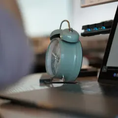 Budzik obok laptopa przypomina o pracy na 3/4 etatu ile to godzin.