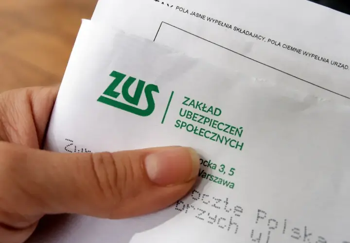 Dłoń trzyma dokument ZUS. Płatnik składek przygotowuje się do wypełnienia formularza.