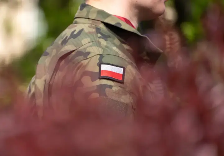 Żołnierz w mundurze moro z polską flagą na ramieniu, symbol służby i przyszłej emerytury policyjnej.