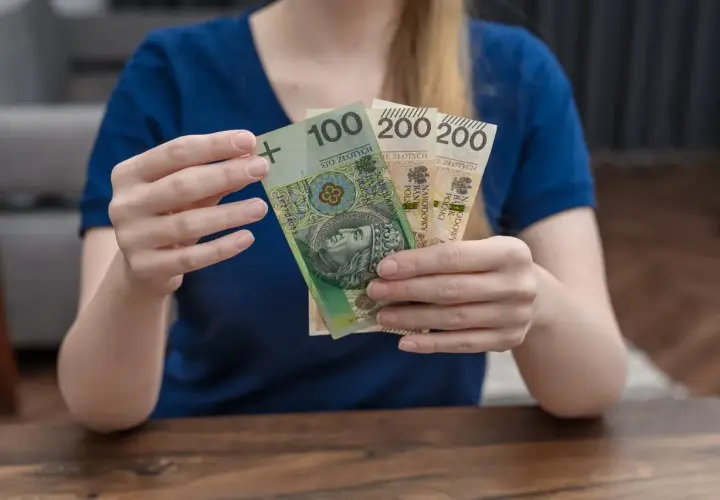 Dłonie trzymają banknoty: 100 zł i dwa po 200 zł. To może być część świadczenia rodzicielskiego.