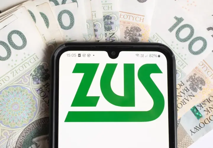 Telefon z aplikacją ZUS na tle banknotów 100 zł. Dostęp do świadczeń dla osoby z niepełnosprawnością.