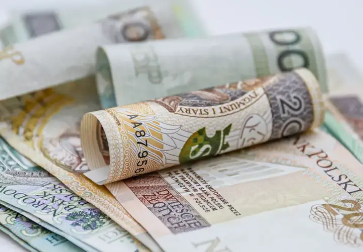 Zwijane polskie banknoty, w tym 20 złotych, symbolizują oszczędności na dodatkowy urlop.