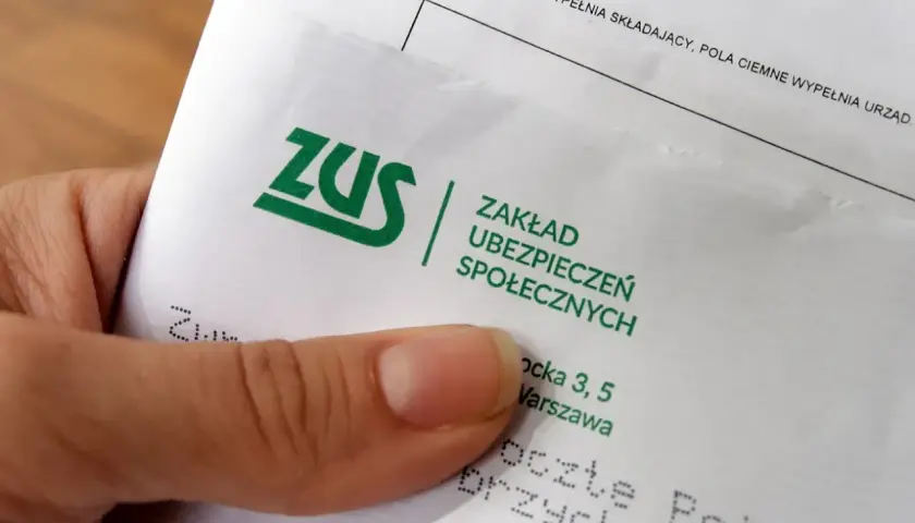 Dłoń trzyma dokument ZUS. Płatnik składek przygotowuje się do wypełnienia formularza.