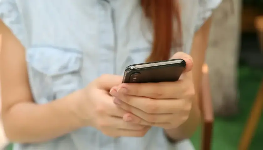 Kobieta w jasnej koszuli trzyma smartfon, szukając informacji, gdzie sprawdzić L4.