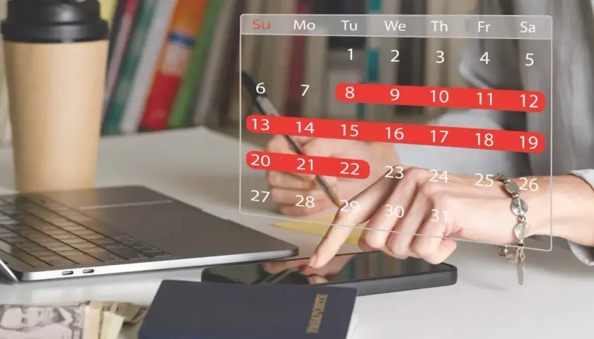 Planowanie urlopu: 26 dni wolnego do wykorzystania. Na biurku laptop, paszport, pieniądze i kalendarz.