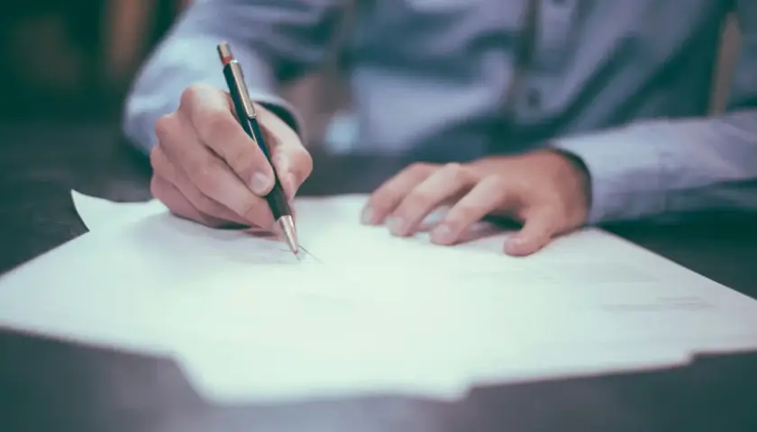 Ręka pisze piórem na papierze. Uczysz się, jak napisać list formalny po ang.