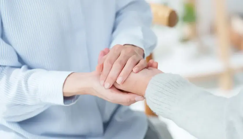 Dwie osoby trzymają się za ręce, symbolizując wsparcie. Może to być związane ze świadczeniem wspierającym 2026 tabela.