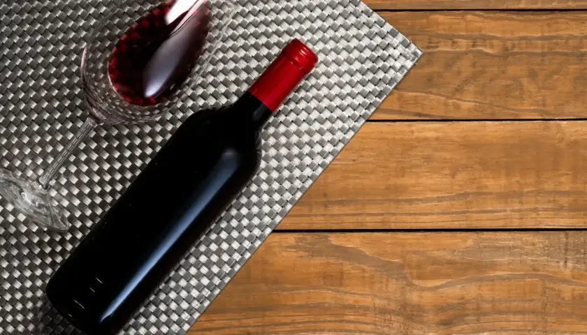 Ciemnoczerwone wino w kieliszku i butelce, gotowe do degustacji przez sommeliera.
