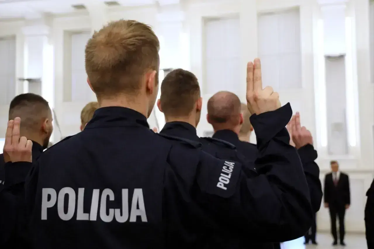 Policjanci w mundurach podnoszą ręce. Czy ich zarobki w policji są adekwatne do służby?