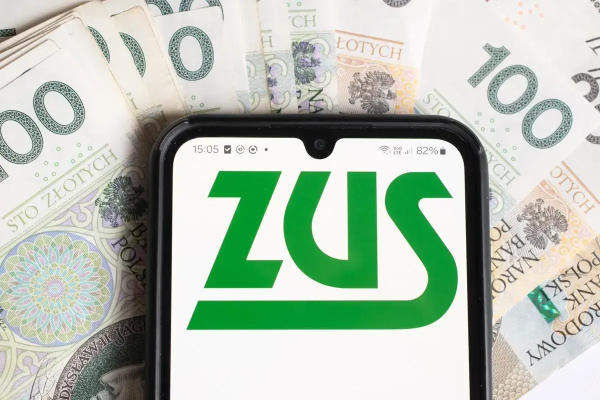Telefon z aplikacją ZUS na tle banknotów 100 zł. Dostęp do świadczeń dla osoby z niepełnosprawnością.