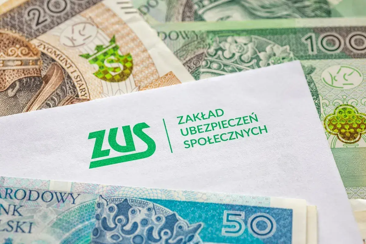Koperta ZUS na tle polskich banknotów symbolizuje ubezpieczenie chorobowe i finansowe bezpieczeństwo.