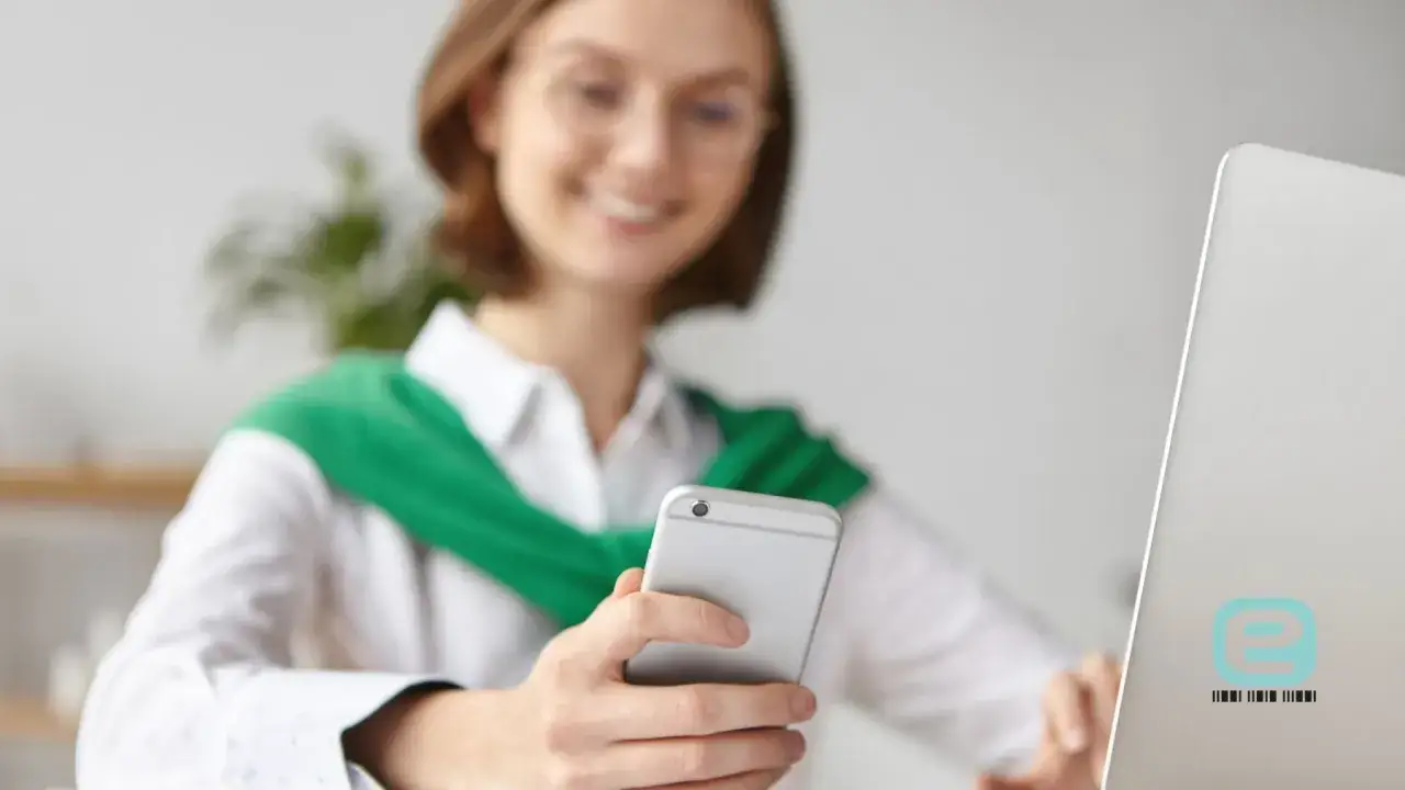 Kobieta sprawdza na telefonie, gdzie sprawdzić L4. Na laptopie widnieje logo.