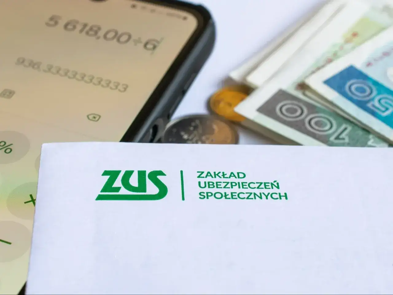 ZUS i pieniądze na koncie. Czy to zapowiedź zwrotu podatku dla emerytów? Obliczenia na telefonie i stos banknotów sugerują finansowe nadzieje.